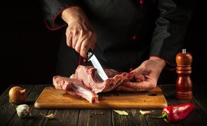 homem com faca de desossar cortando carne